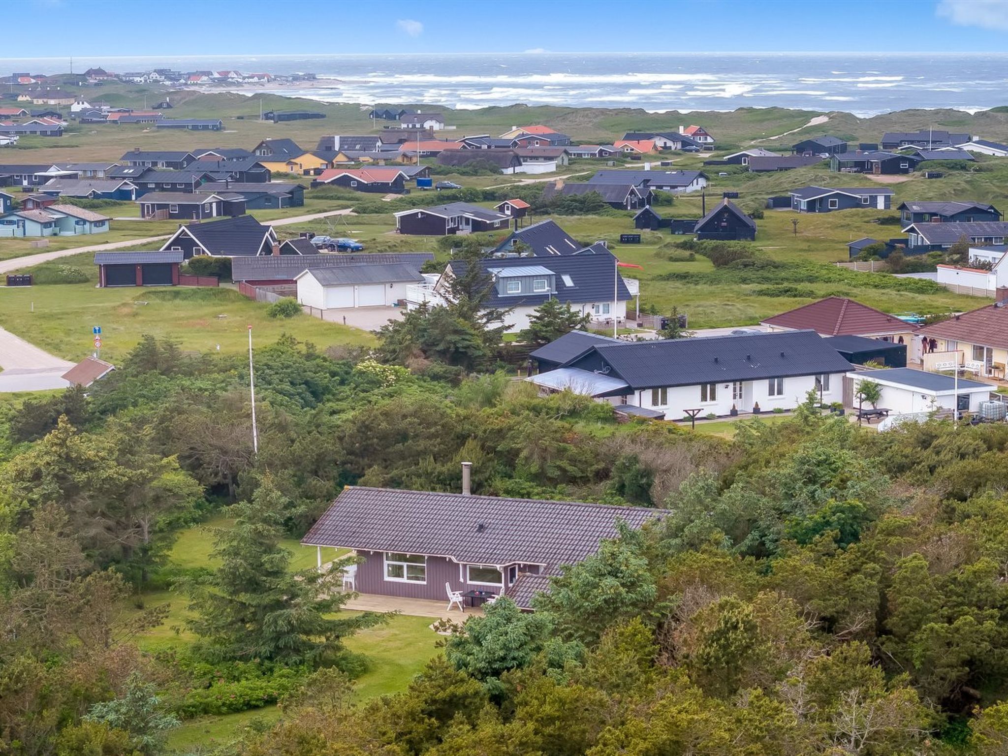 Un quartier résidentiel situé sur la côte, avec des maisons, dont certaines sont dotées de garages attenants, et un paysage verdoyant.