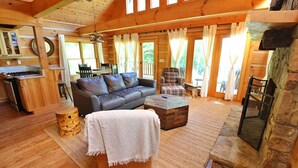 A cozy cabin interior with a wooden floor, a sofa, a coffee table, and a fireplace.