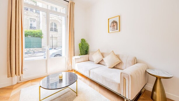 Un salon moderne avec un canapé, une table basse en verre et une petite table ronde.