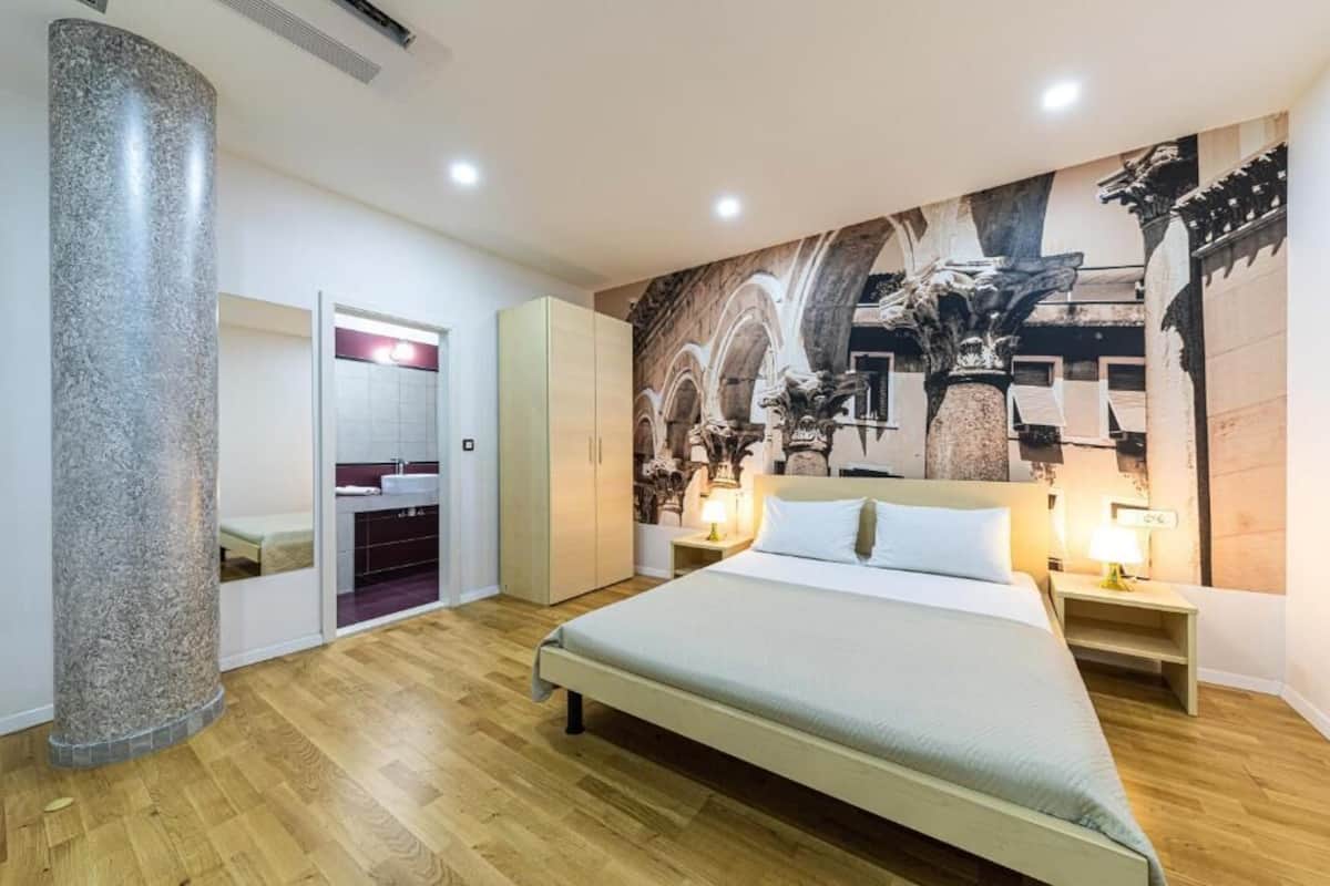 Un dormitorio moderno con una cama grande, un armario, un espejo y un mural en la pared.