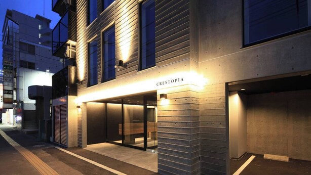 Un edificio moderno con escaparate llamado "CRESTOPIA" y entrada de garaje visible.