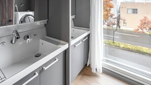 Un baño moderno con muebles grises, un lavamanos blanco y un espejo grande.