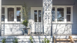 Une maison blanche avec un porche, un pot de fleurs et un banc en bois.