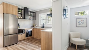 Une cuisine moderne avec des meubles en bois, des appareils en acier inoxydable et un plan de travail blanc.
