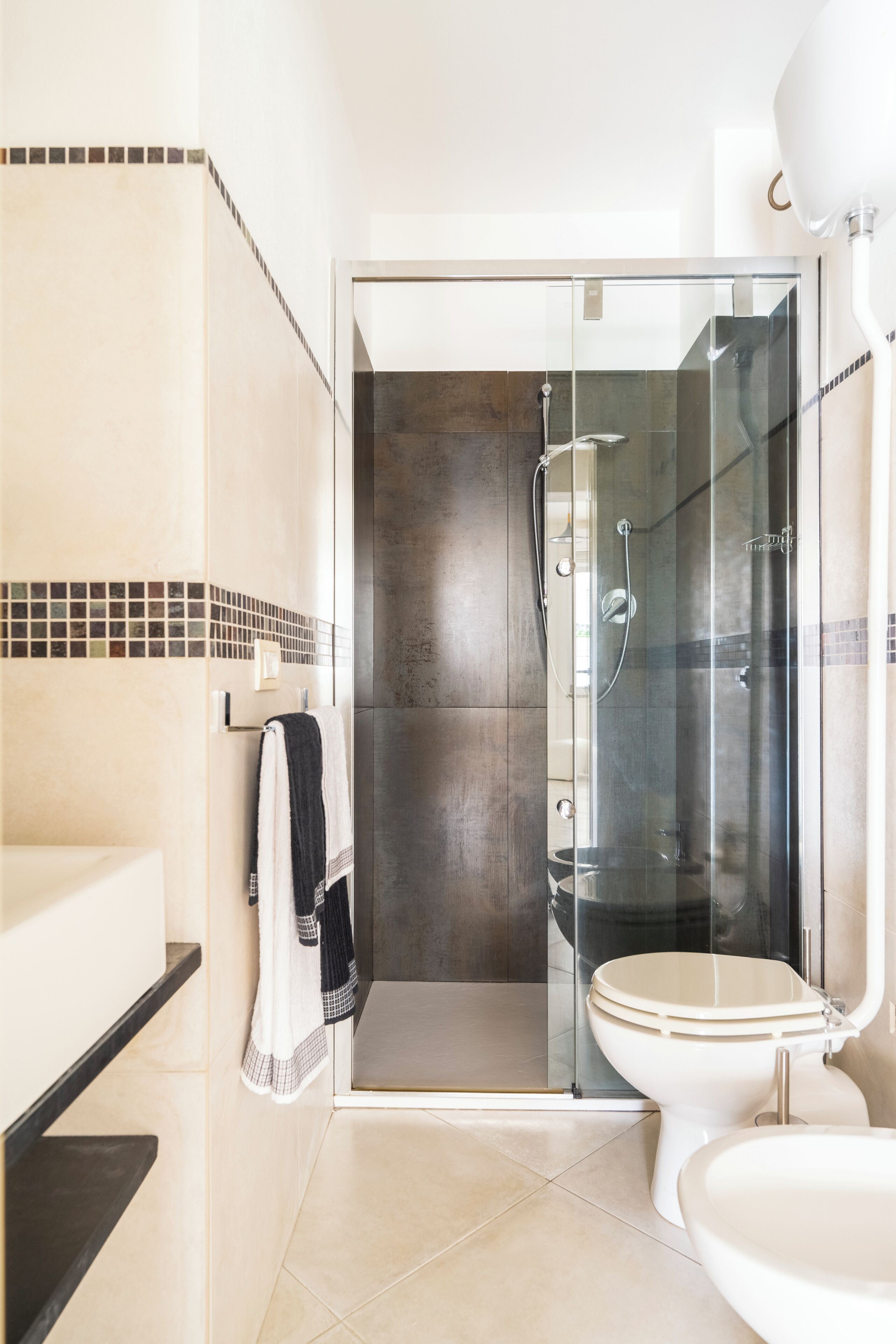 A modern bathroom with a glass-enclosed shower, a white toilet, and a black sink.