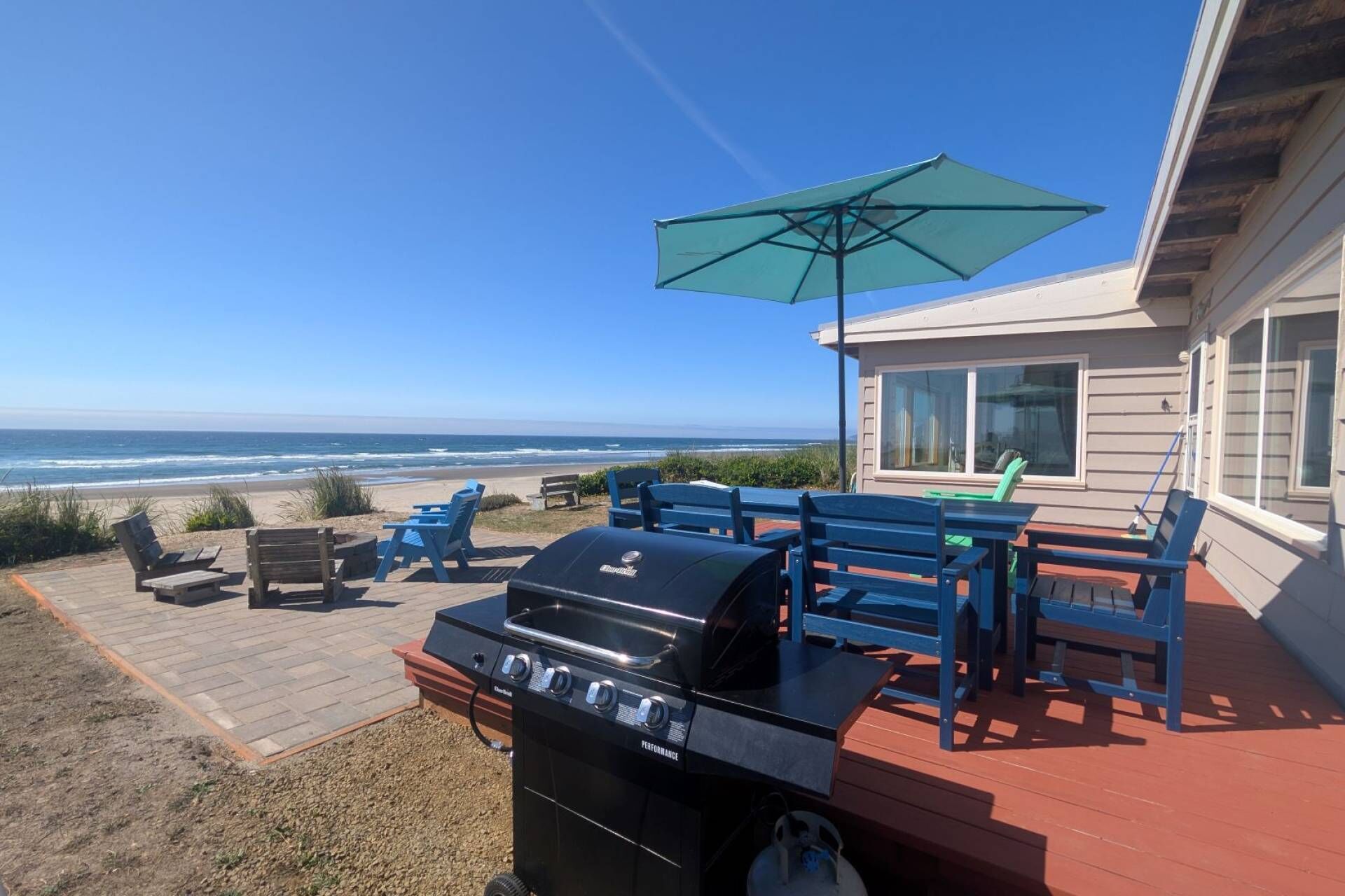 Un patio con una parrilla, mobiliario exterior y vistas al océano.