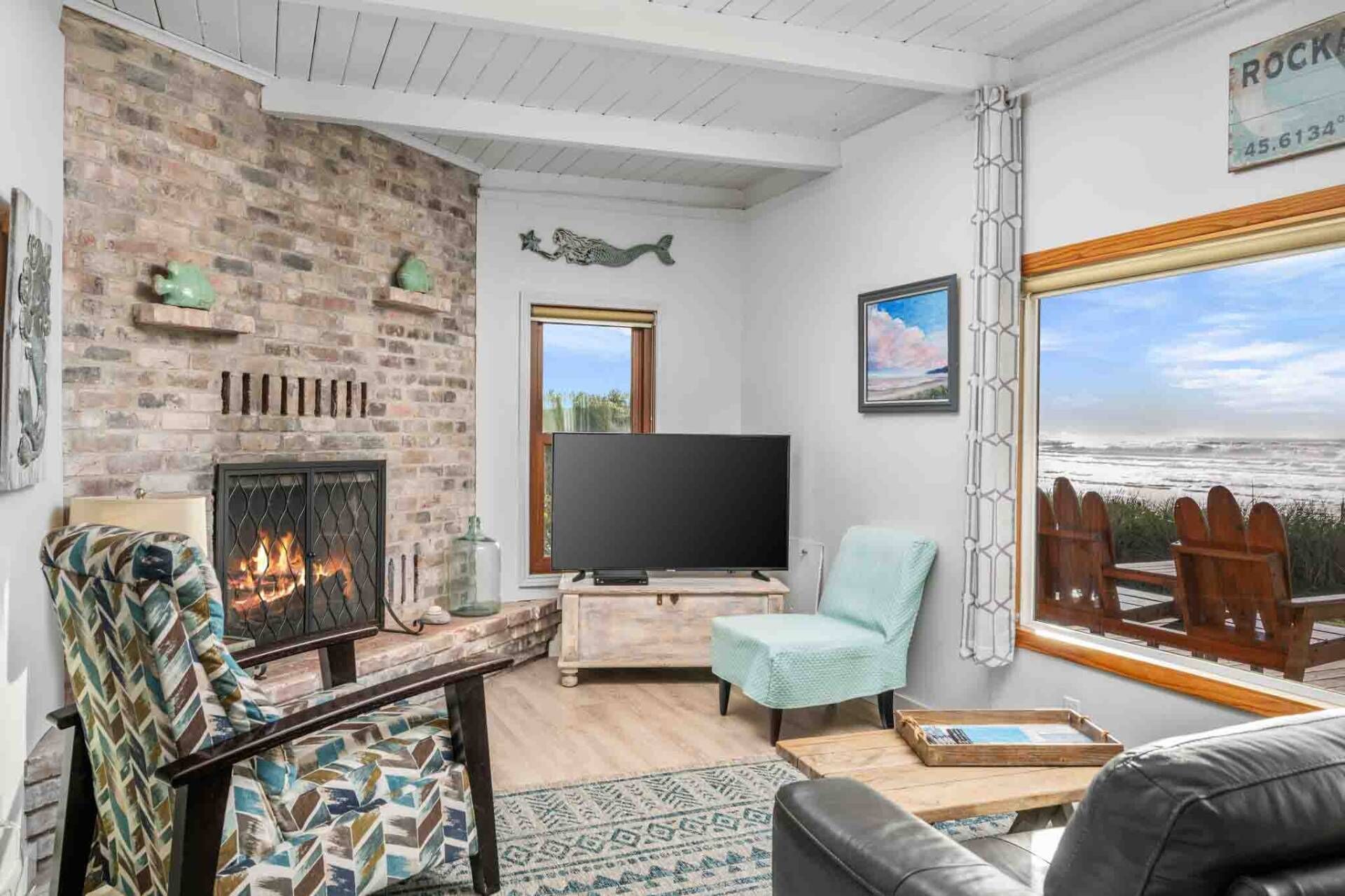 Ein gemütliches Wohnzimmer mit Kamin, Fernseher und Meerblick.