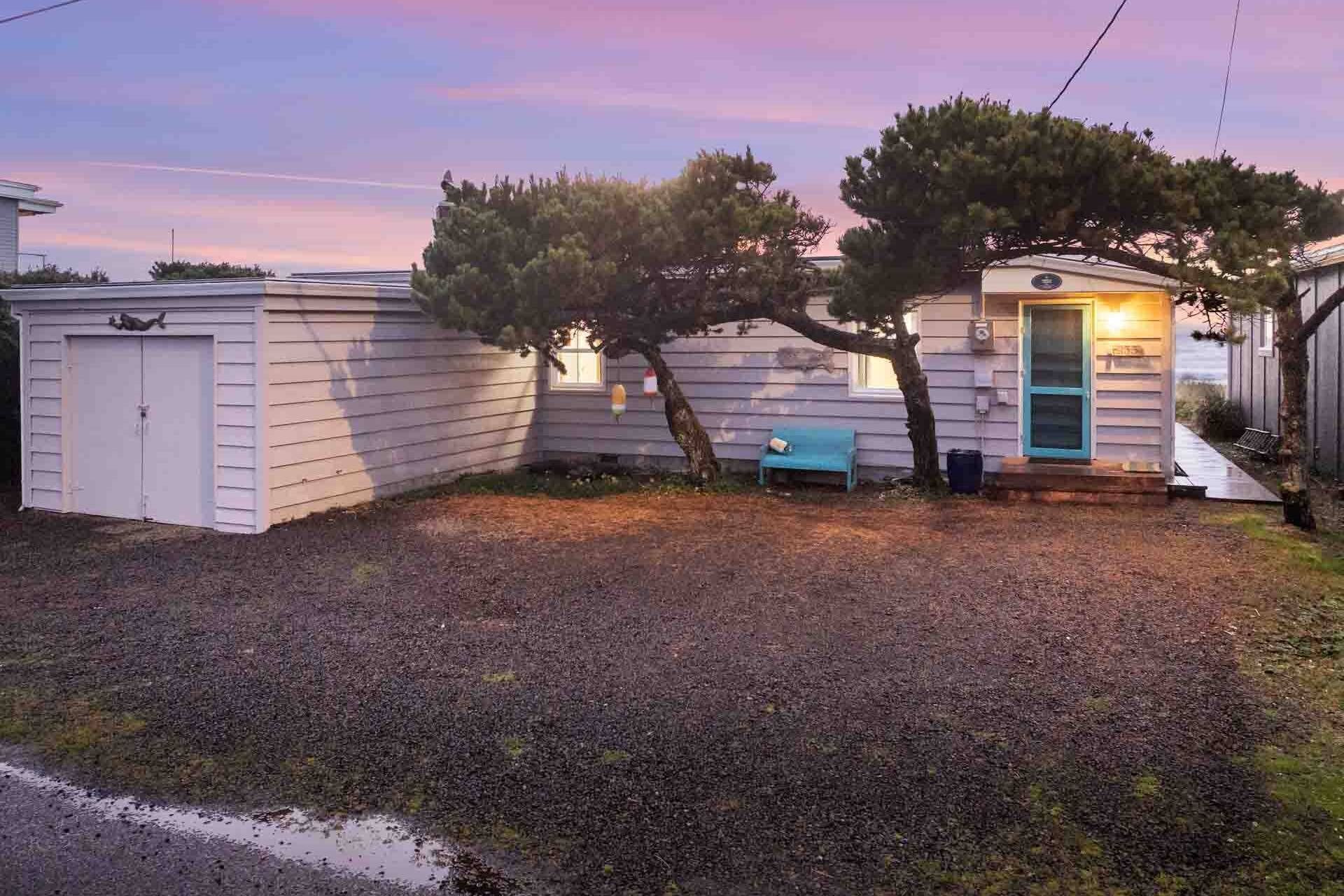 Una casita de un solo piso con una puerta azul y un porche.