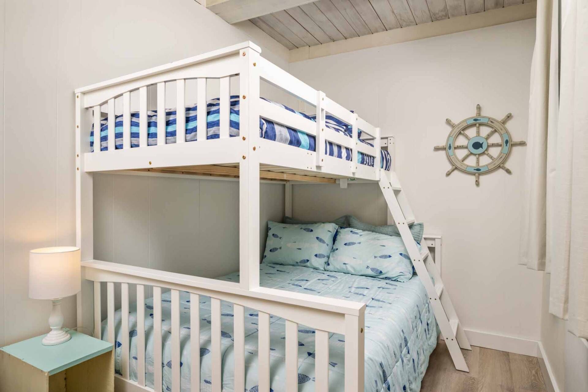 A bunk bed with a nautical-themed wall decoration and a ladder.