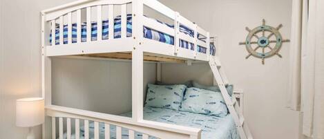 A bunk bed with a nautical-themed wall decoration and a ladder.