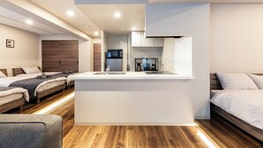A modern, compact living space with a kitchenette, two beds, and a small seating area. - NOBLE 302 (Sapporo)