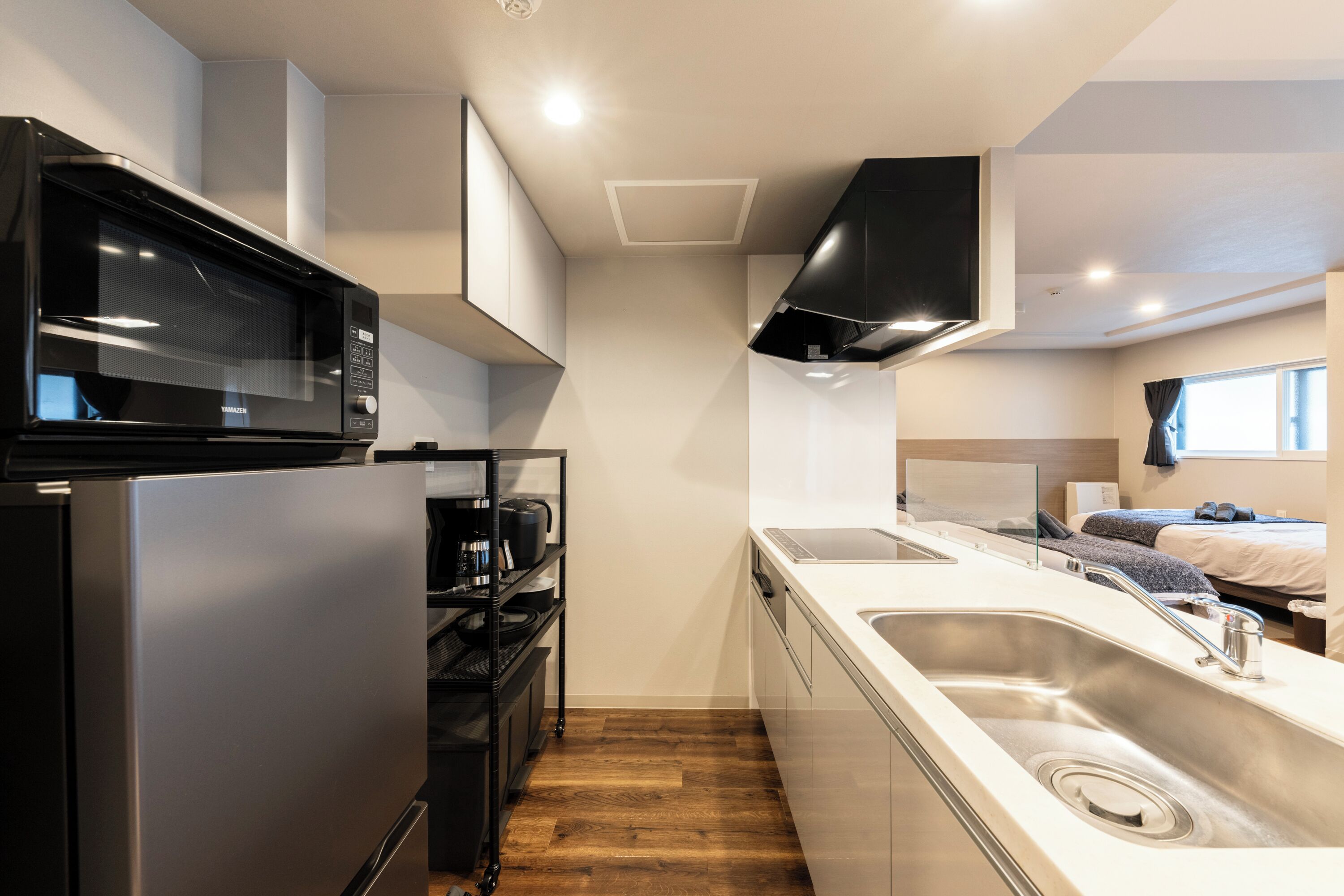 Una kitchenette compacta con refrigerador de acero inoxidable, microondas y lavamanos.
