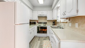A modern kitchen with white cabinets, a built-in oven, a microwave, and a sink. - Hot Tub & Fire Pit: Holiday Island Getaway! (Holiday Island)
