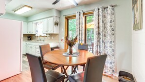 A dining area with a round table, chairs, a ceiling fan, and a window with curtains. - Hot Tub & Fire Pit: Holiday Island Getaway! (Holiday Island)