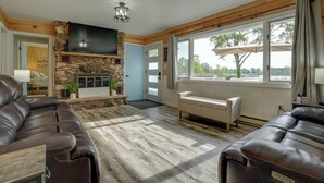 A spacious living room with a stone fireplace, leather sofas, and a large TV. - Lakefront Home in Hartford: Hot Tub, Kayaks & Dock (Hartford)