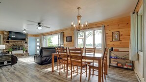 A spacious living area with a dining table, chairs, a fireplace, a television, and a ceiling fan. - Lakefront Home in Hartford: Hot Tub, Kayaks & Dock (Hartford)
