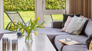 Ein modernes Wohnzimmer mit grauem Sofa, Couchtisch und einer Vase mit gelben Tulpen.