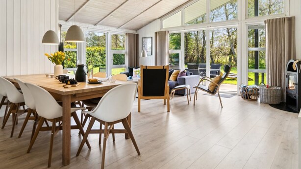 Ein geräumiges Zimmer mit einem Holzesstisch, weißen Stühlen, einer Couch und einem Kamin.