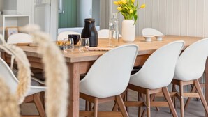Ein Essbereich mit Holztisch, weißen Stühlen und Pendelleuchten.