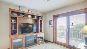 A living room with a wooden entertainment center, a television, and a sliding glass door leading to a balcony.