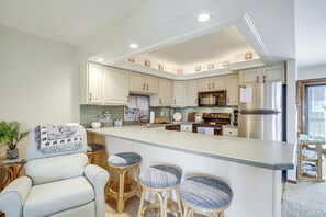 A spacious kitchen with white cabinetry, a large island with bar stools, and stainless steel appliances. - Steps to OC Boardwalk! Family Beach Retreat (Ocean City)