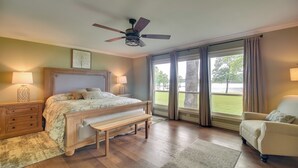 Een slaapkamer met een bed, een bankje, een stoel, een nachtkastje en een plafondventilator.
