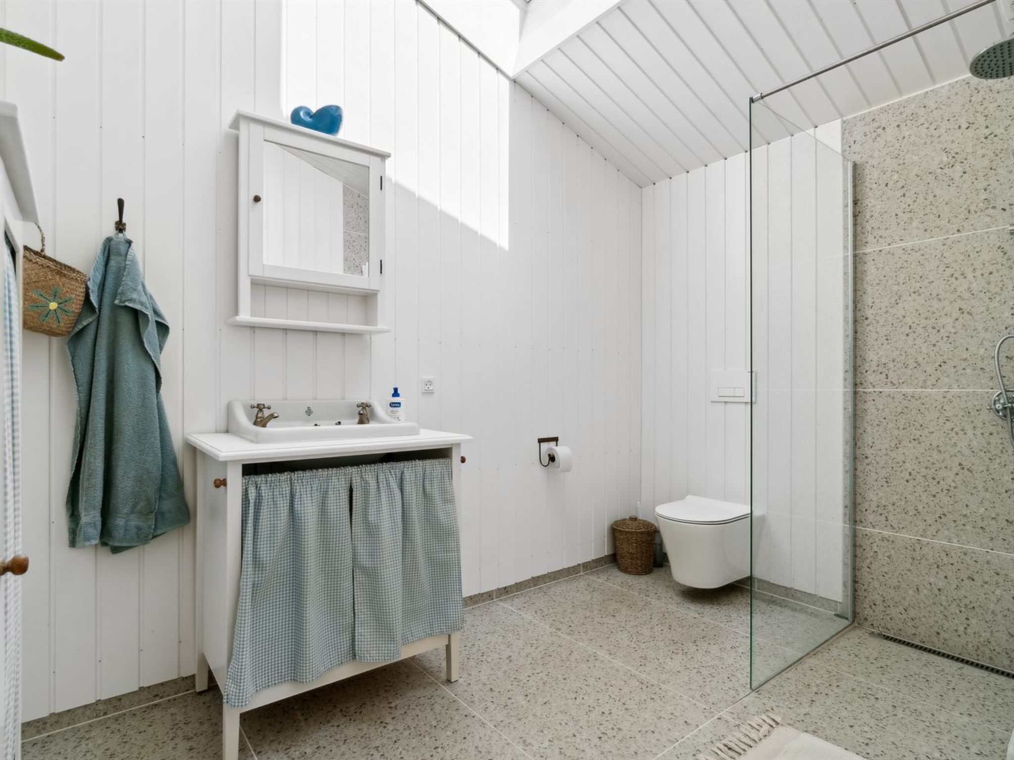 A modern bathroom with a glass shower enclosure, white cabinetry, and a visible toilet.