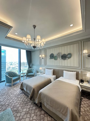 A hotel room with two beds, a chandelier, a view of the city, and a decorative wall. - T-city Presidential Hotel (Tashkent)