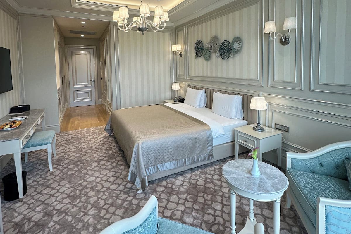 A hotel room with a bed, a desk, a chair, a round table, and a sofa.