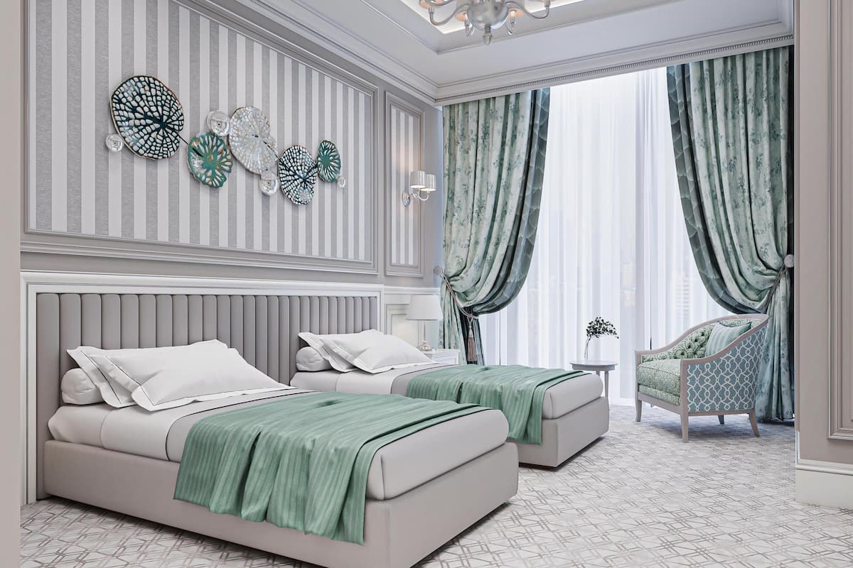 A bedroom with two beds, a chaise lounge, and a decorative wall panel.