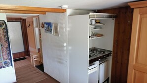 A compact kitchen with a stove, white cabinets, and a small refrigerator. - Studio Apartment 'Heustüble' with Shared Terrace and Wi-Fi (Hinterzarten)