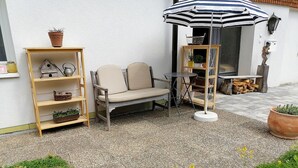A patio with a sofa, a small table, a striped umbrella, and potted plants. - Studio Apartment 'Heustüble' with Shared Terrace and Wi-Fi (Hinterzarten)