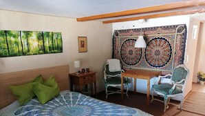 A room with a bed, a table, two chairs, a tapestry, and a painting on the wall. - Studio Apartment 'Heustüble' with Shared Terrace and Wi-Fi (Hinterzarten)
