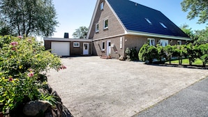 Uma casa de dois andares com telhado inclinado, garagem frontal e entrada pavimentada.