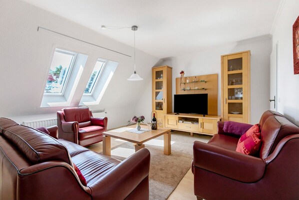 A modern living room with a sofa set, a coffee table, a TV, and built-in shelving.