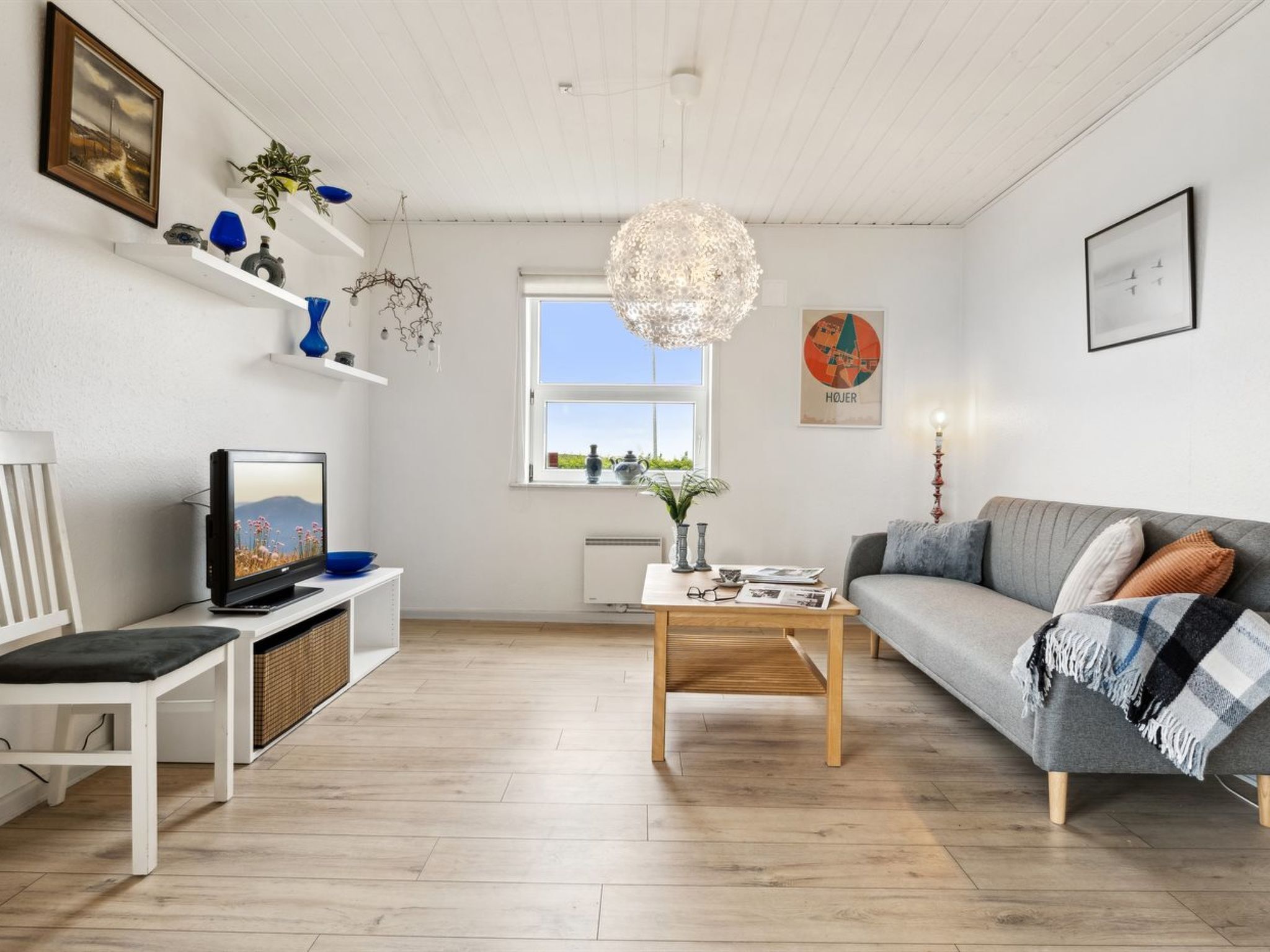 Uma sala de estar moderna com televisão, sofá, mesa de centro e objetos decorativos.