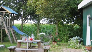 Ein Holztisch für ein Picknick mit Bänken, einer Rutsche und Blumentöpfen in einem Garten.
