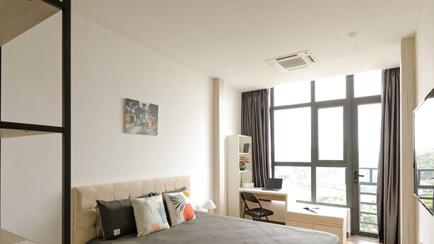 A modern hotel room with a large bed, a desk with a computer, and a view of the outdoors through large windows. - HoLo Kim Ma Hanoi (Hanoi)