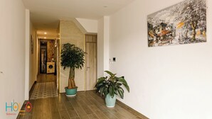 A hallway with wooden flooring, a potted tree, and a painting on the wall. - HoLo Kim Ma Hanoi (Hanoi)