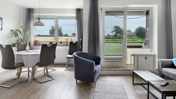 Una sala de estar moderna con comedor, ventanas grandes y vistas al exterior.