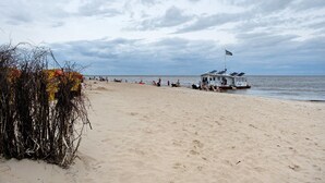 Una playa con un puesto de socorristas, una lancha pequeña y una orilla arenosa.