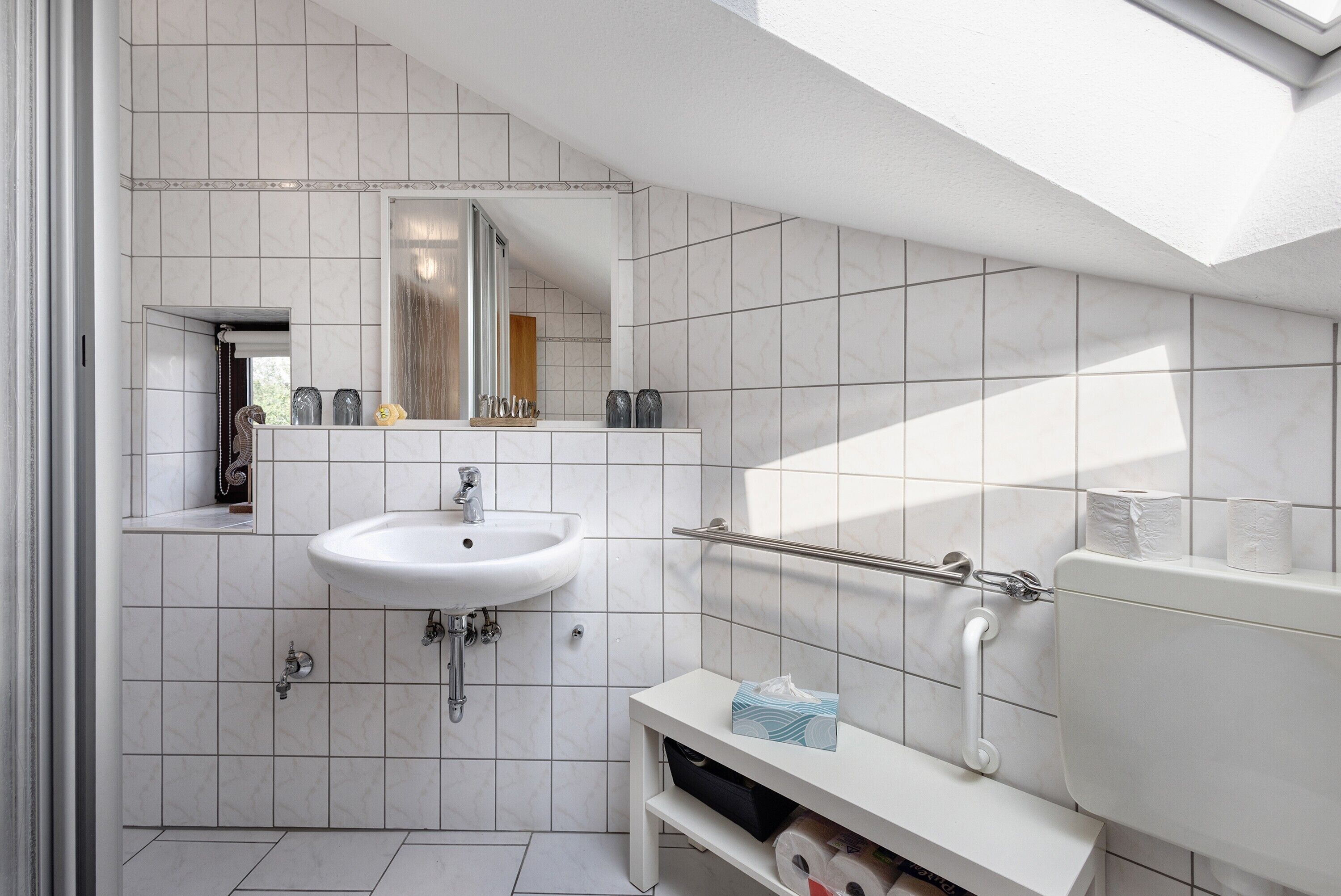 A modern bathroom with a white sink, mirror, and toilet.