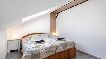 Ein Schlafzimmer mit einem Holzbett, einem weißen Nachttisch, einer Nachttischlampe und einem Oberlicht.