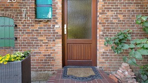 A brick building with a wooden door, a mailbox, and a flower planter. - Apartment 'Ferienwohnung Thomée' with Terrace and Wi-Fi (Looft)