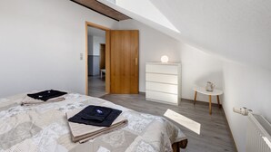 A bedroom with a skylight, a wooden door, a bedside table with a lamp, and a radiator. - Apartment 'Ferienwohnung Thomée' with Terrace and Wi-Fi (Looft)