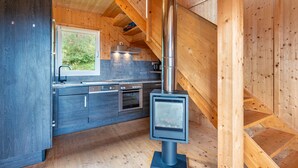 Cocina moderna con estufa de leña, horno integrado y ventana con vistas a la vegetación.