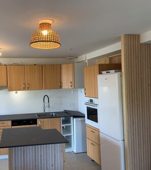 A modern kitchen with wooden cabinets, a built-in oven, and a black countertop.