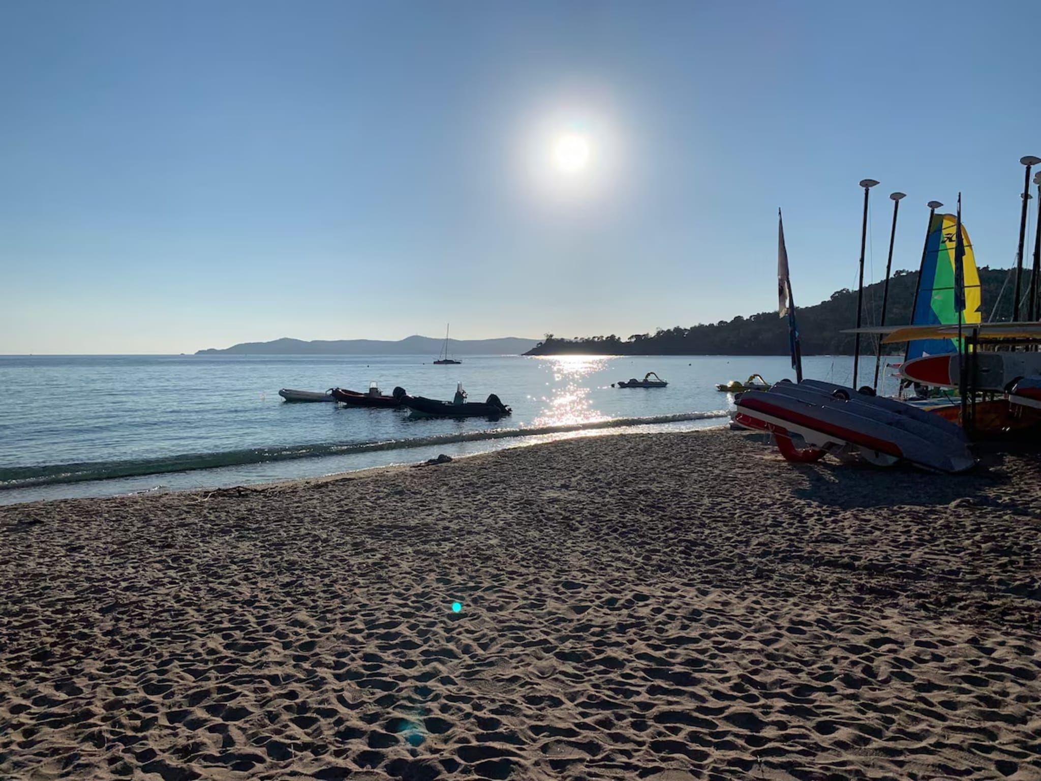 A beach with boats, a clear sky, and a distant mountain range.