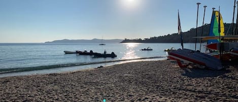 A beach with boats, a clear sky, and a distant mountain range.