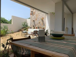 An outdoor dining area with a table, chairs, and a stone wall backdrop.